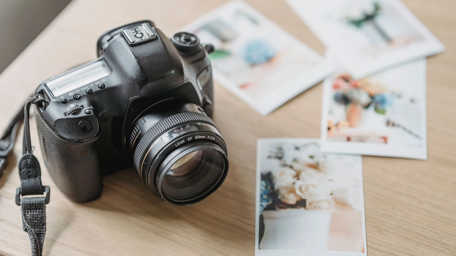 Camera and printed photographs arranged on a table for portfolio review