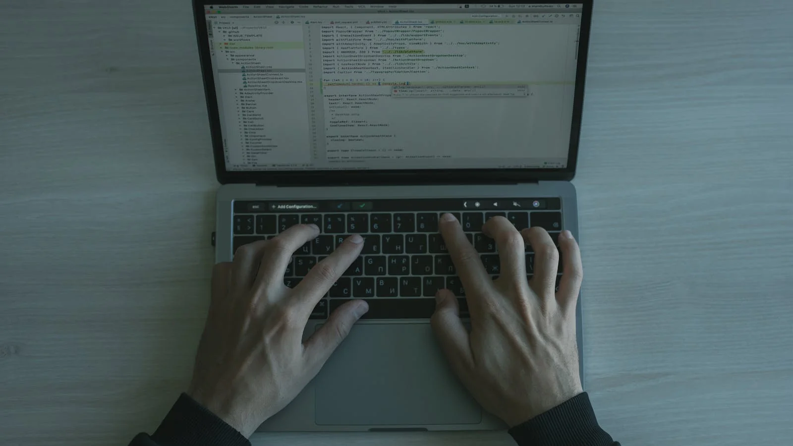 Programmer's hands on a laptop keyboard at a dim desk, the workflow that produces AI optimized FAQs