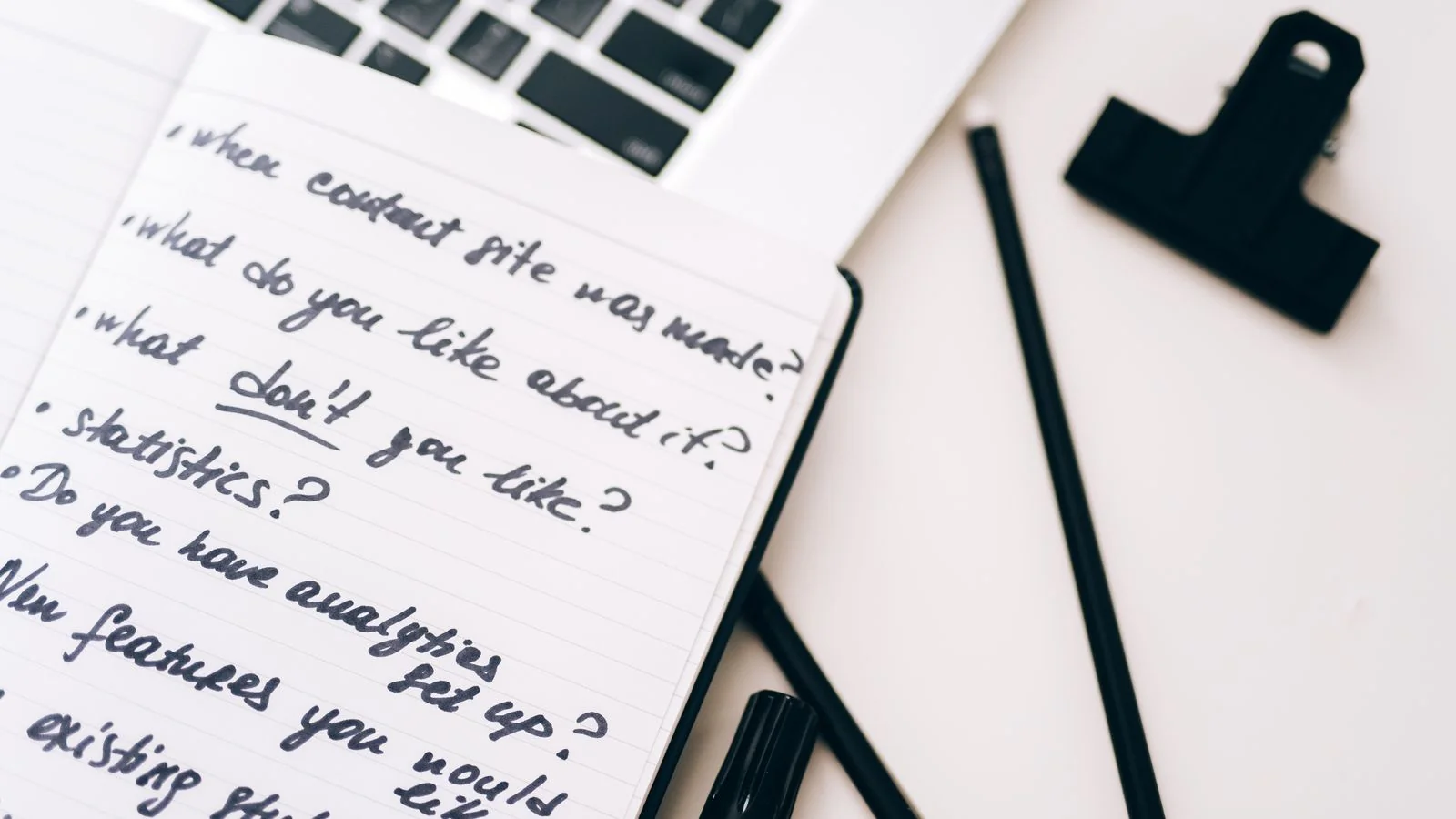 An open notebook with handwritten notes next to a laptop, the focused planning a single call to action requires