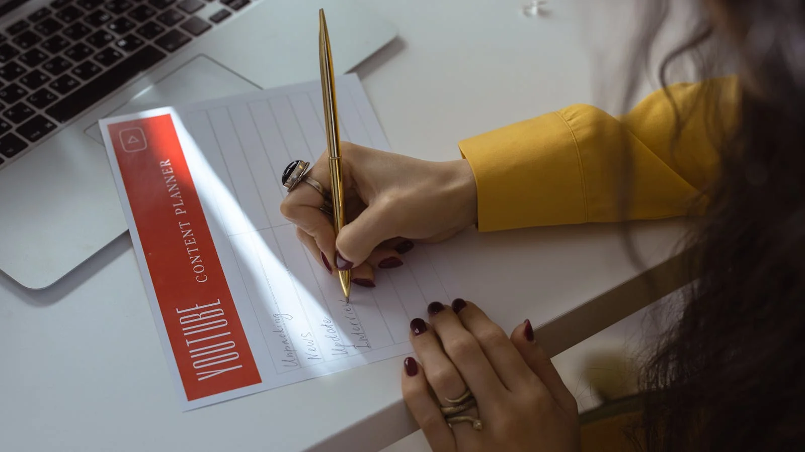 A hand writing in a content planner at a desk, the deliberate mapping a strong hub page requires