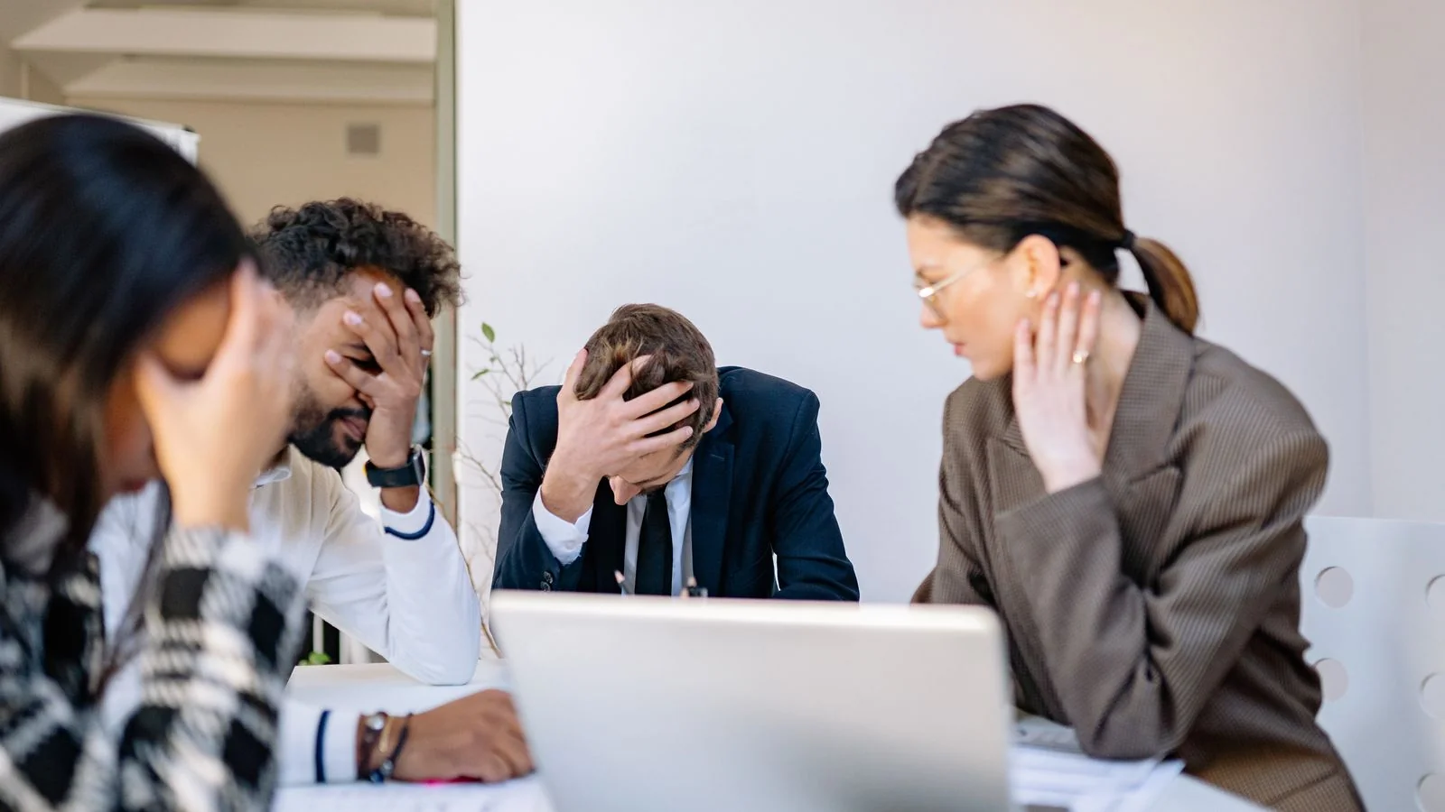 Stressed colleagues around a table in an office, the team assembling in the opening minutes of a crisis