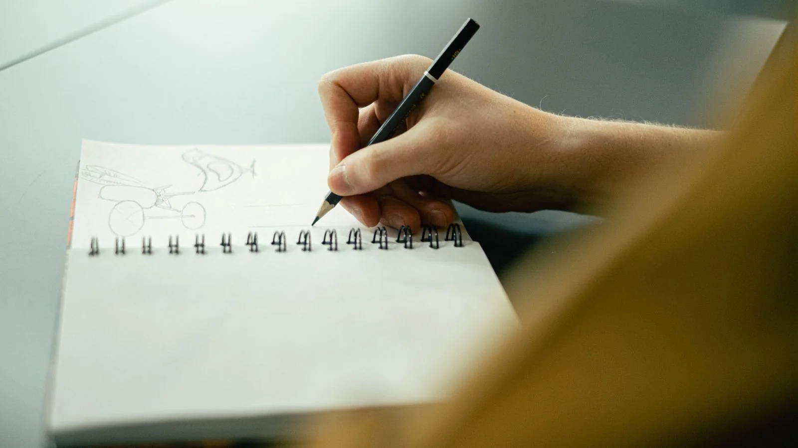 Hand sketching ideas in a notebook with a pencil, planning a pitch