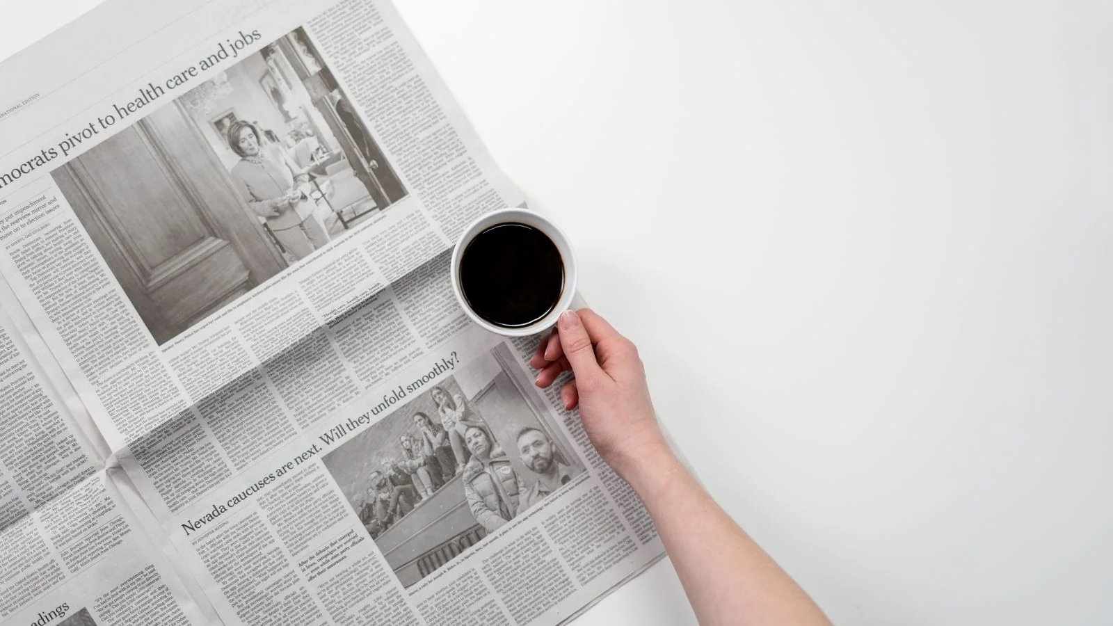 A cup of black coffee held over a folded business newspaper, the daily trade-press reading habit