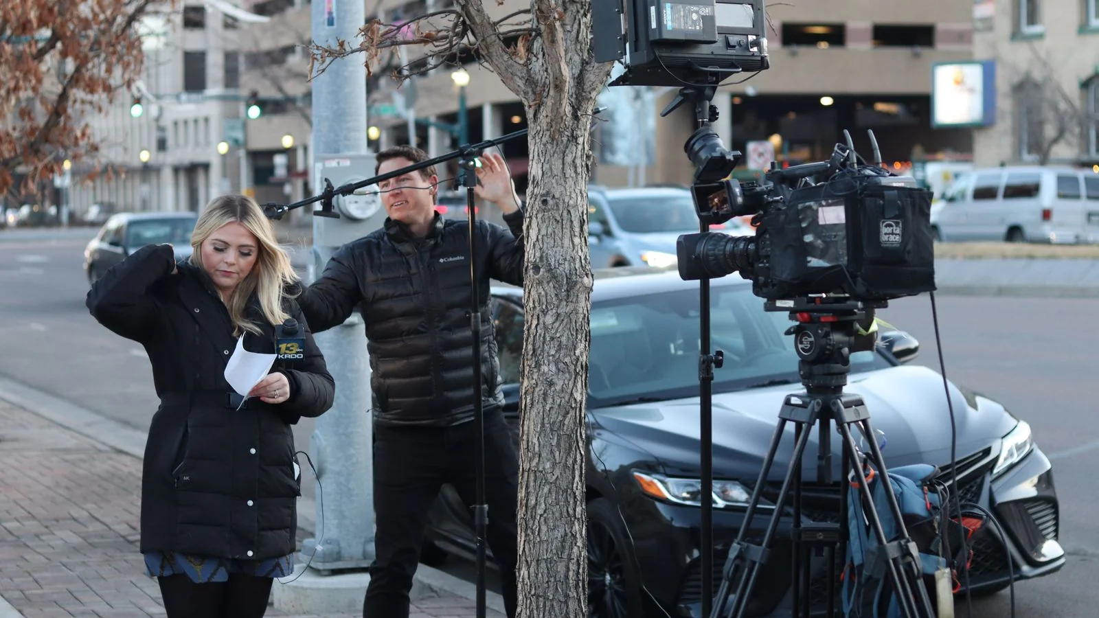News crew with a camera reporting from a city street