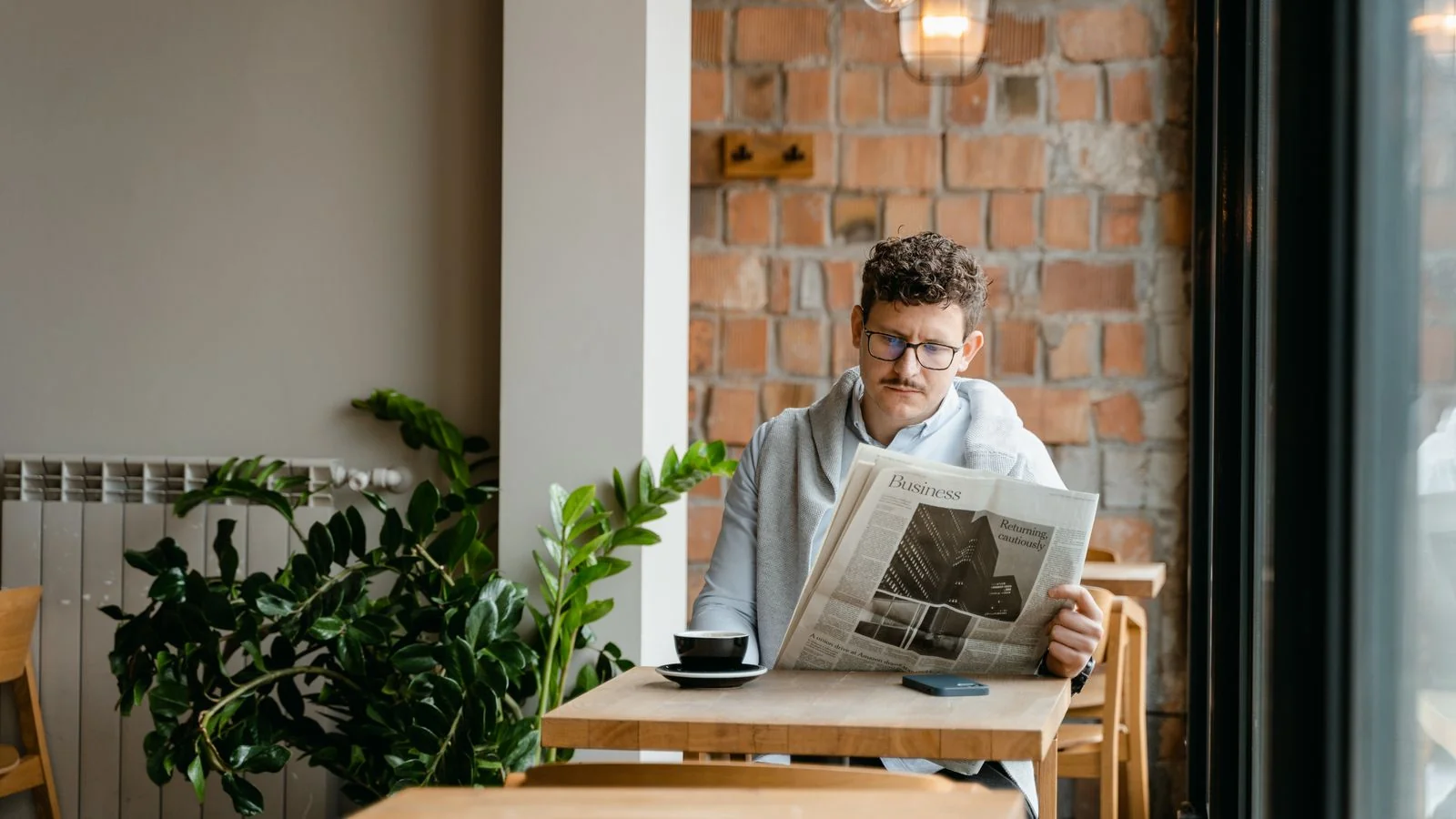 A man reading a newspaper over coffee, the unhurried weekly read Barron's is built for