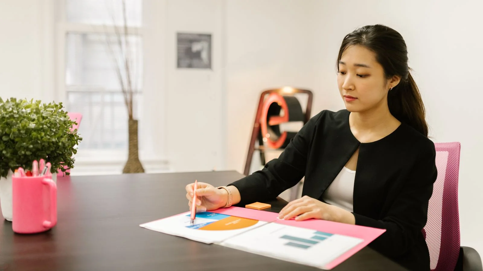 A woman reviewing documents and charts at her desk, the preparation an editor can verify before replying