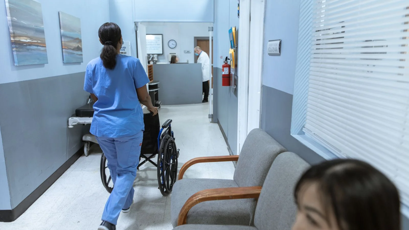 Nurse pushing a wheelchair down a bright hospital corridor during patient care