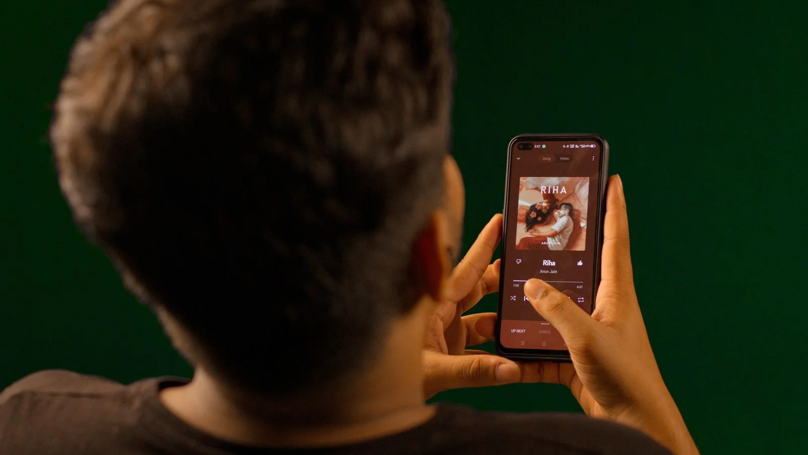 Person holding a smartphone and streaming music through headphones