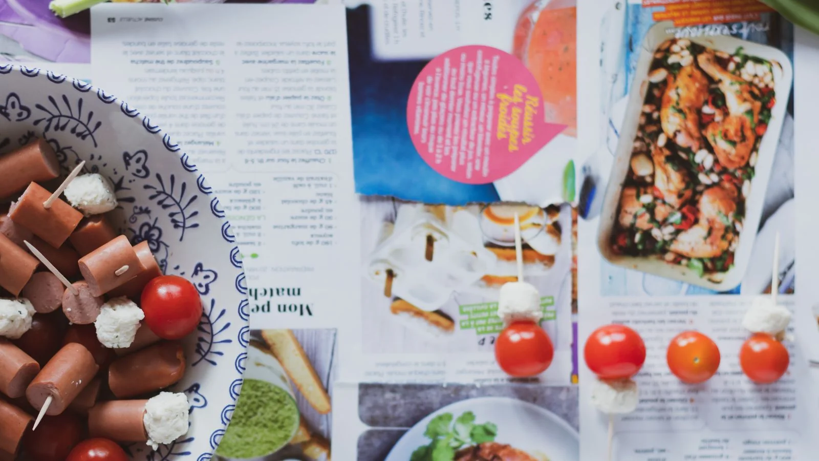 A slice of layered cake on a plate beside an open magazine on a wooden table
