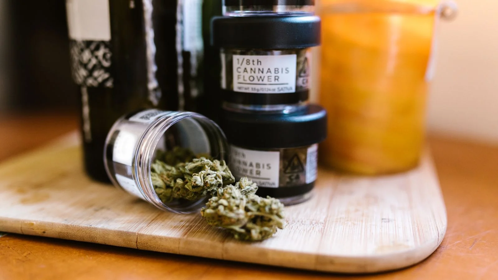 Cannabis buds rest in a clear glass jar on a wooden surface under soft light