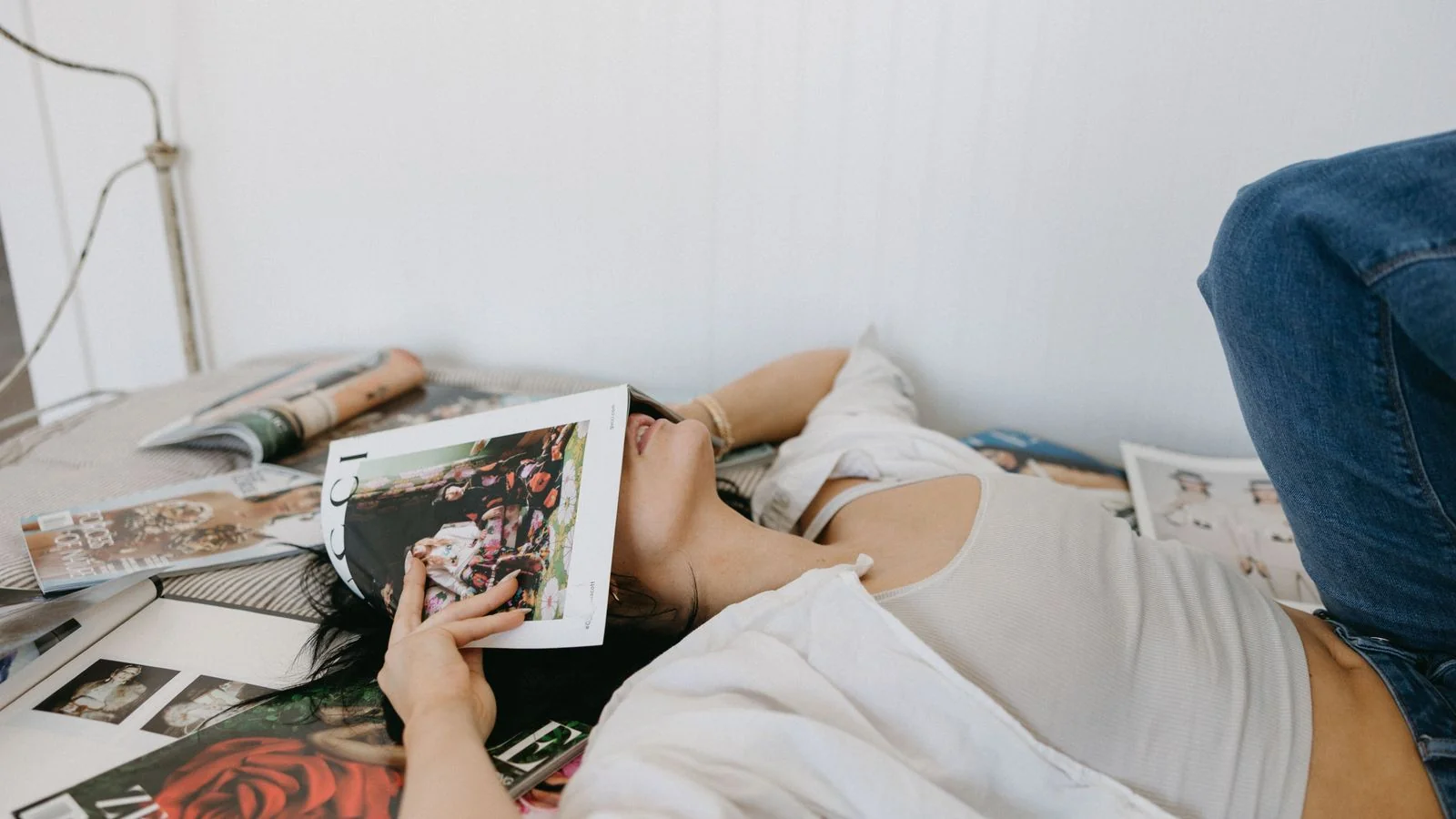 A woman browsing through a stack of magazines spread across a table