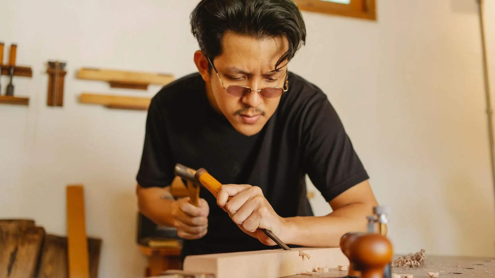Woodworker using a chisel and hammer to cut a notch in a hardwood plank