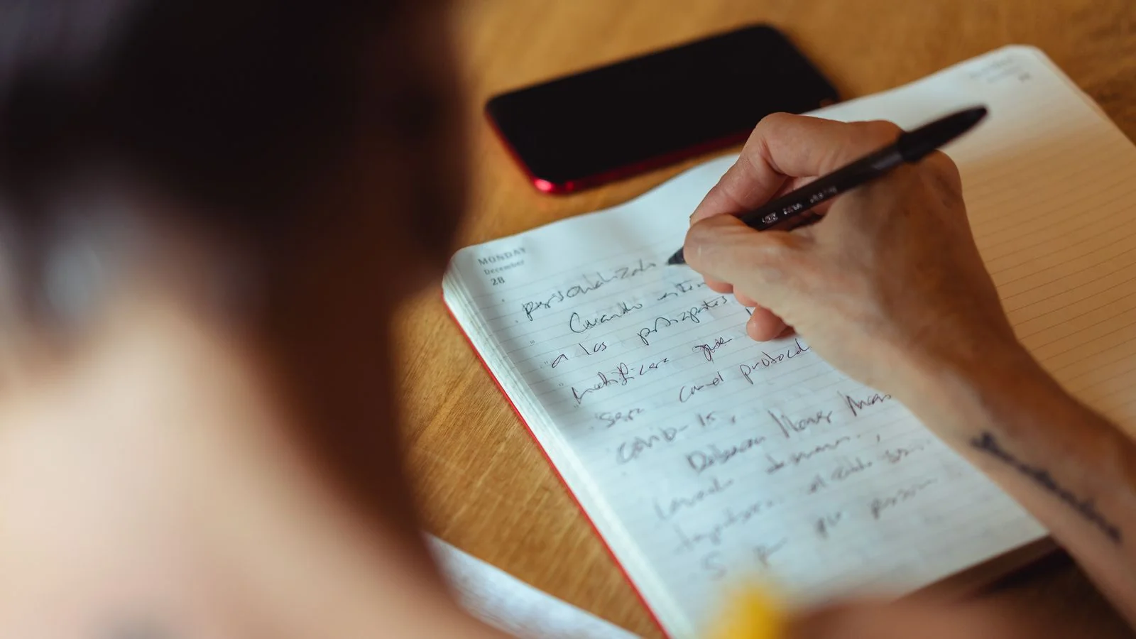 Person writing in a notebook at a desk, the reporter shaping a local pitch into a story