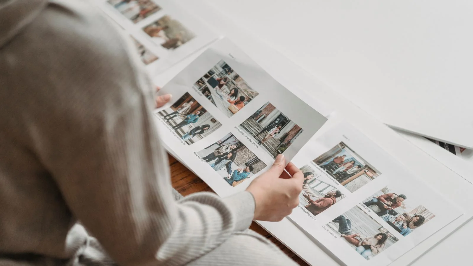 Person sorting through printed photos in an album, choosing a first-look image to pitch