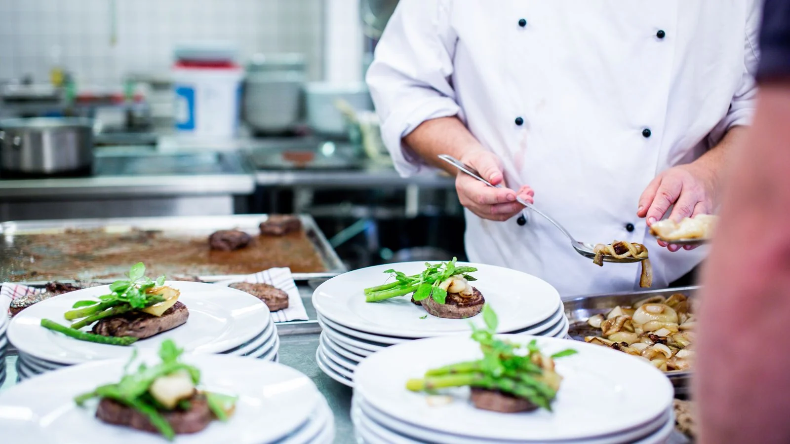 Chef in a professional kitchen preparing plates for service, the operation behind a one-line story