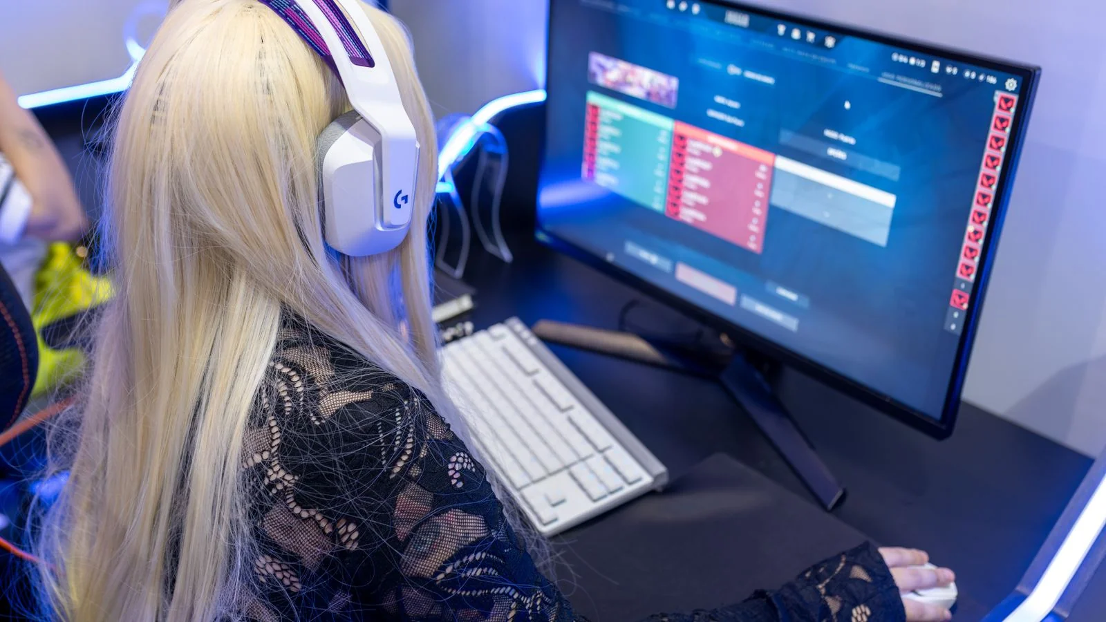 A focused gamer wearing a headset playing a video game on a desktop computer