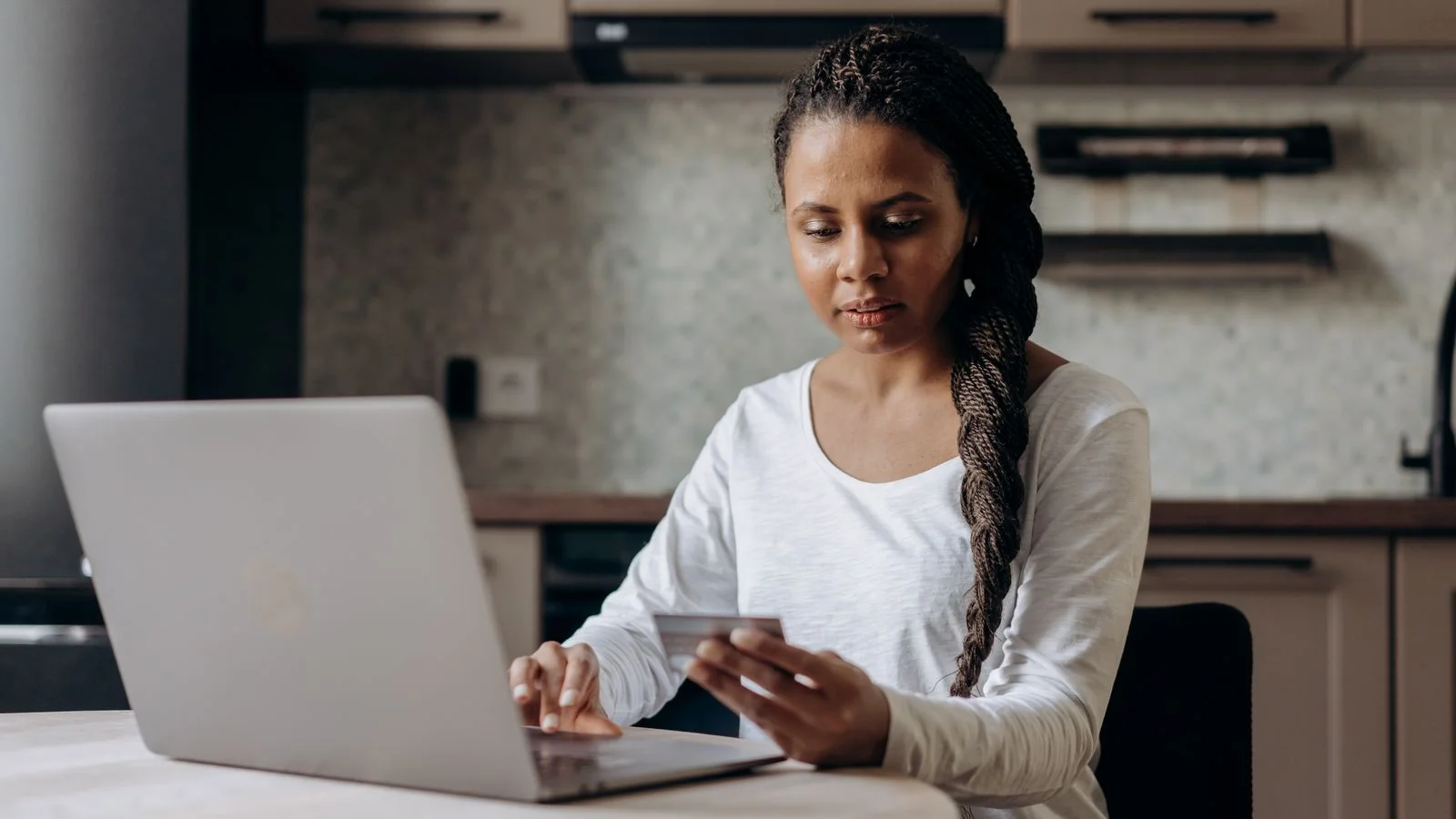 Woman at home using a laptop and credit card to shop online