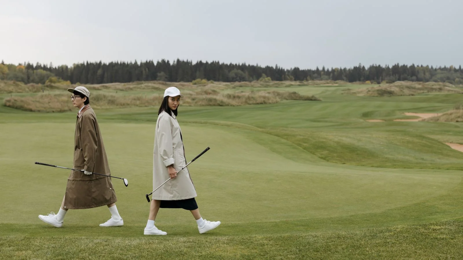 Two golfers walking across an open fairway on a bright day