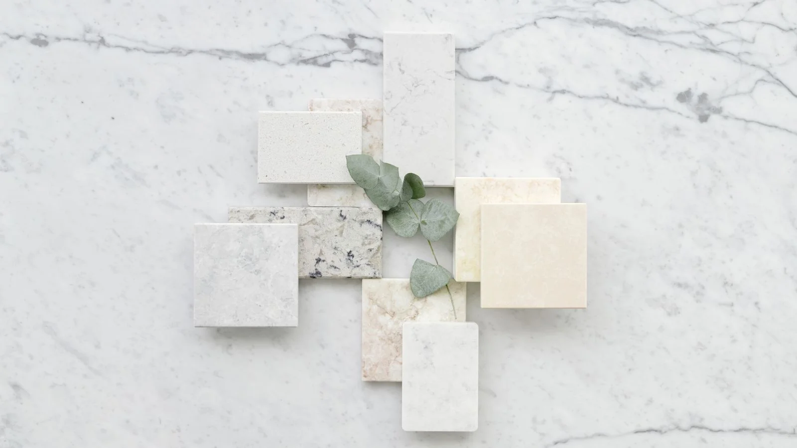 Marble tile samples arranged with eucalyptus leaves, the kind of material story House Beautiful renovation coverage runs on