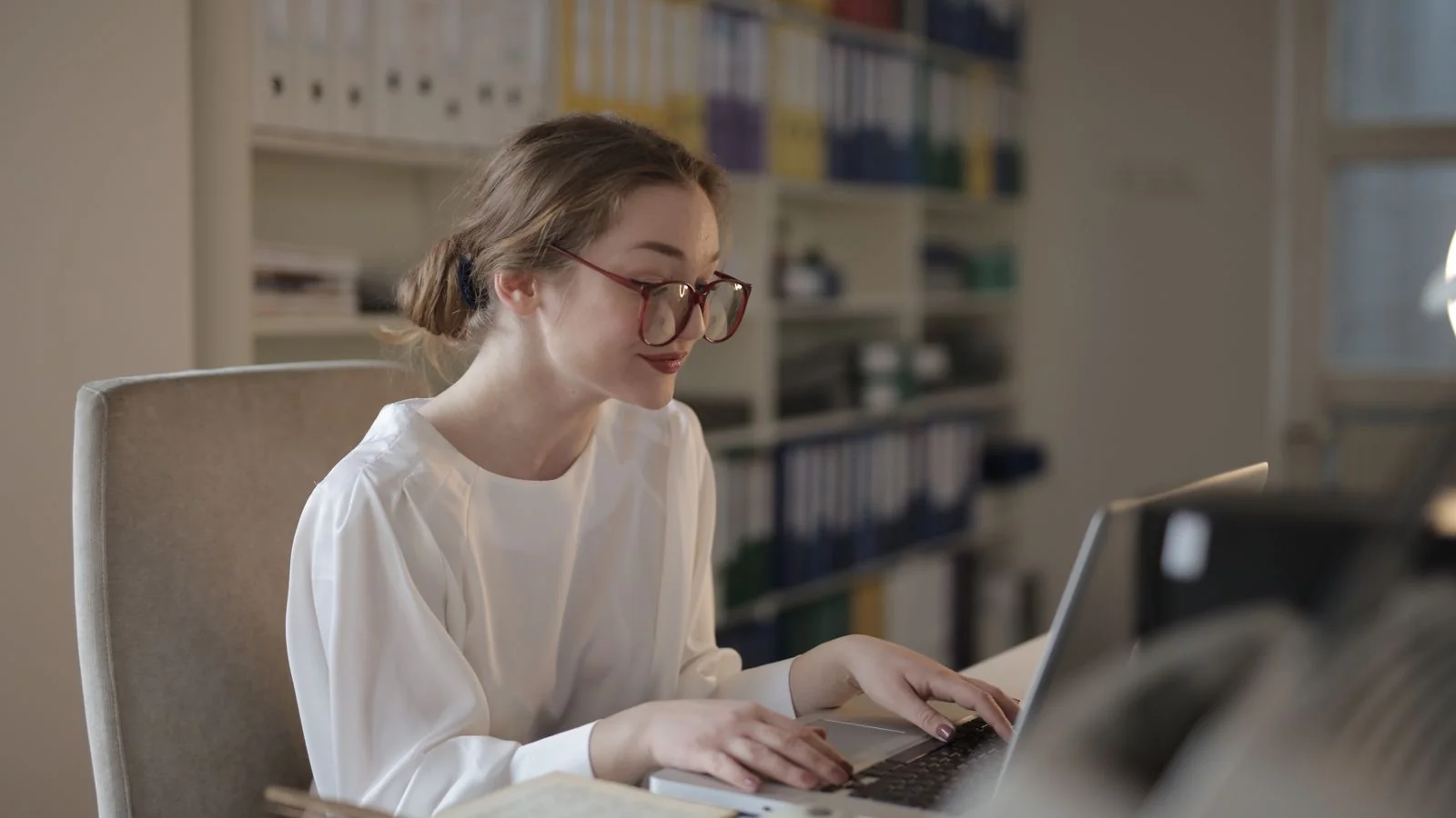 Professional woman focused on her laptop at a modern desk, reviewing incoming pitches