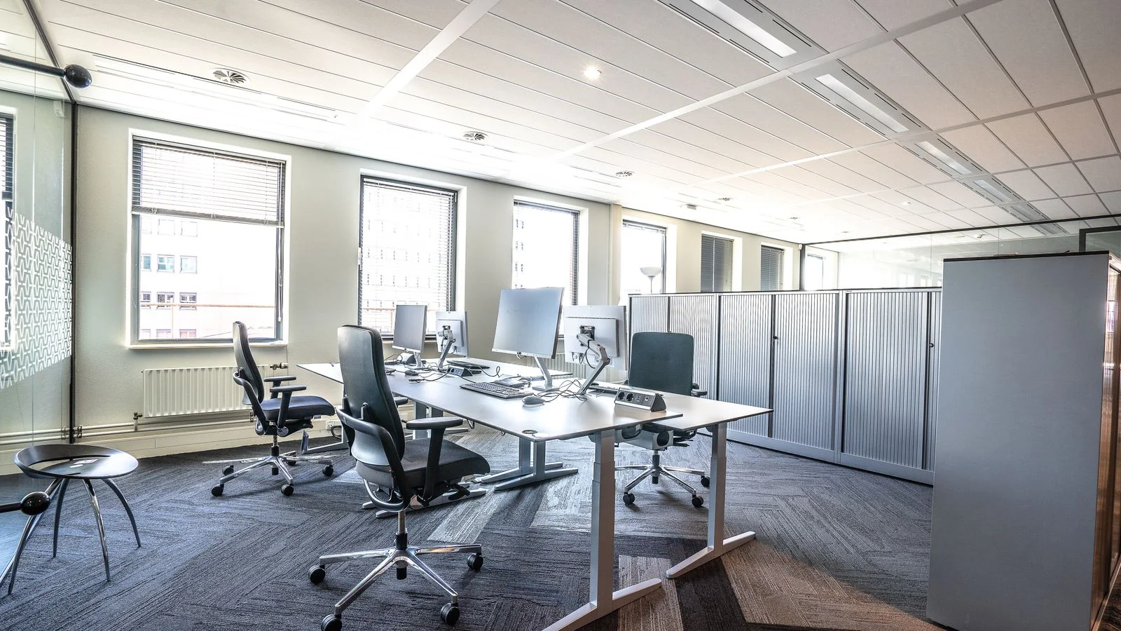 Bright modern open-plan newsroom office with workstations and ergonomic chairs