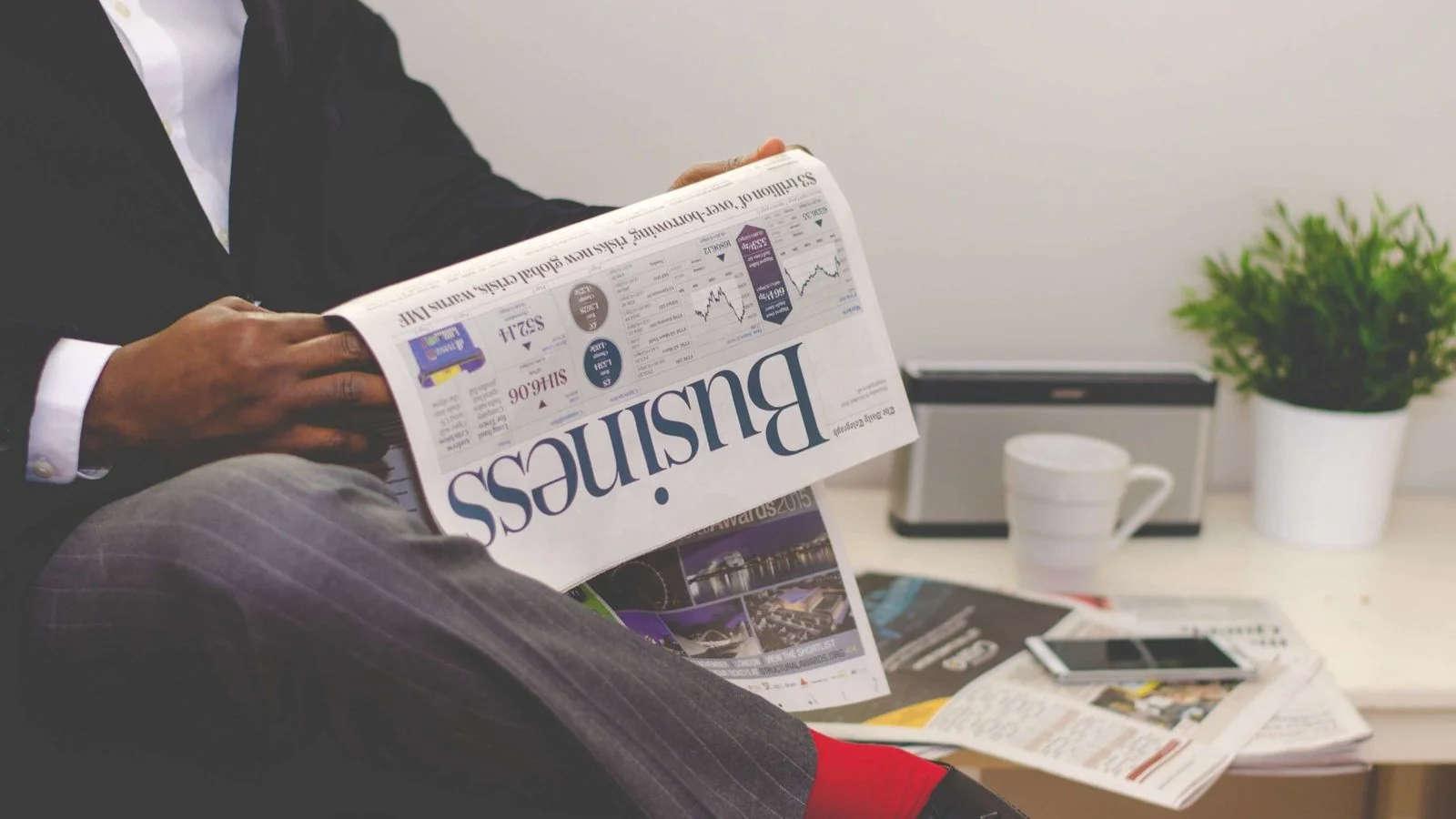 Businessman reading a financial newspaper at a desk, the reader a MarketWatch story is written to serve