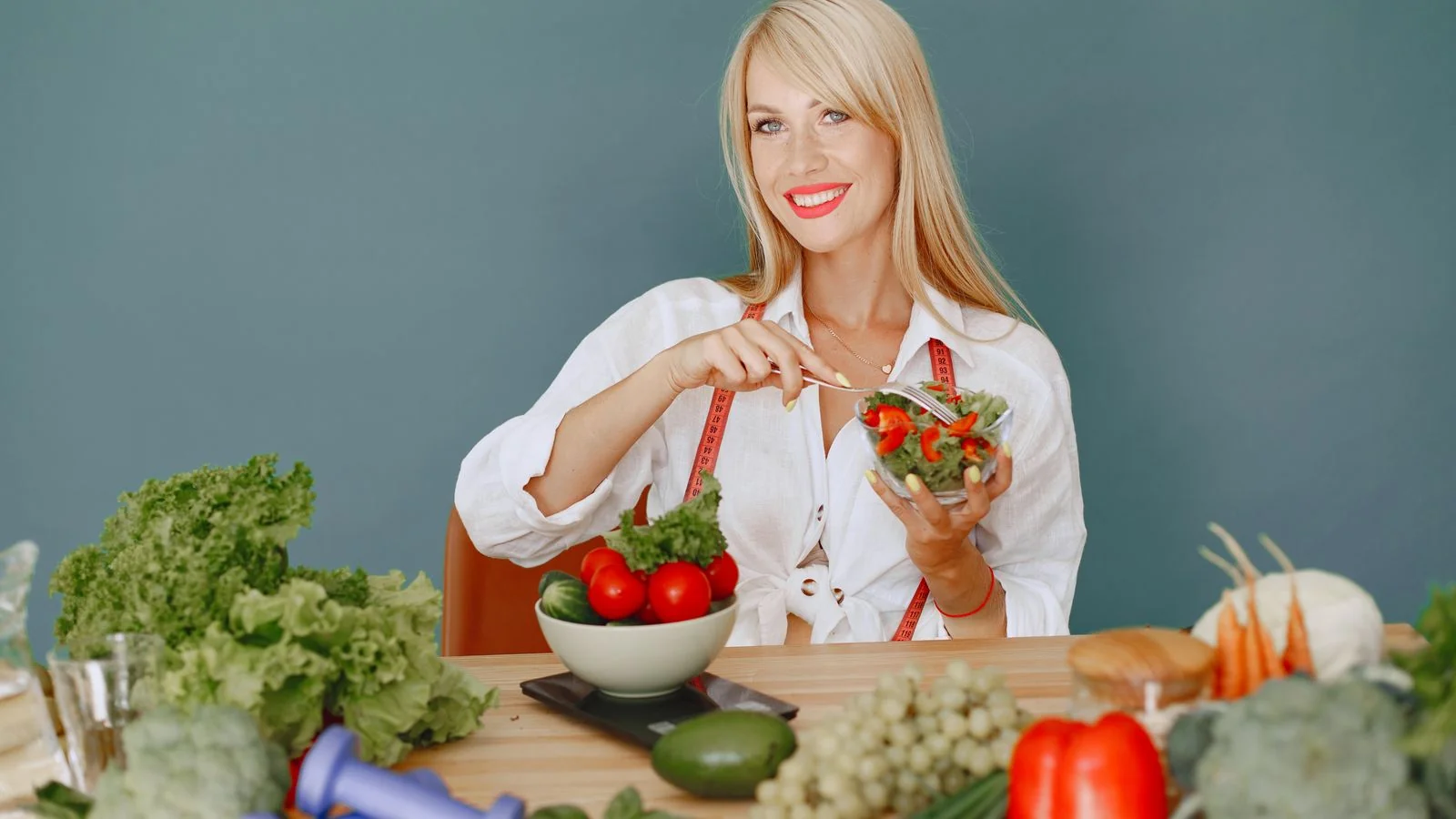 A person in athletic wear holding a fresh, colorful salad bowl at a kitchen counter