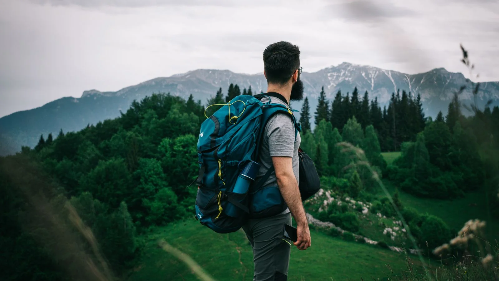 Hiker with a backpack overlooking a vast mountain valley, the kind of scene a Men's Journal writer covers