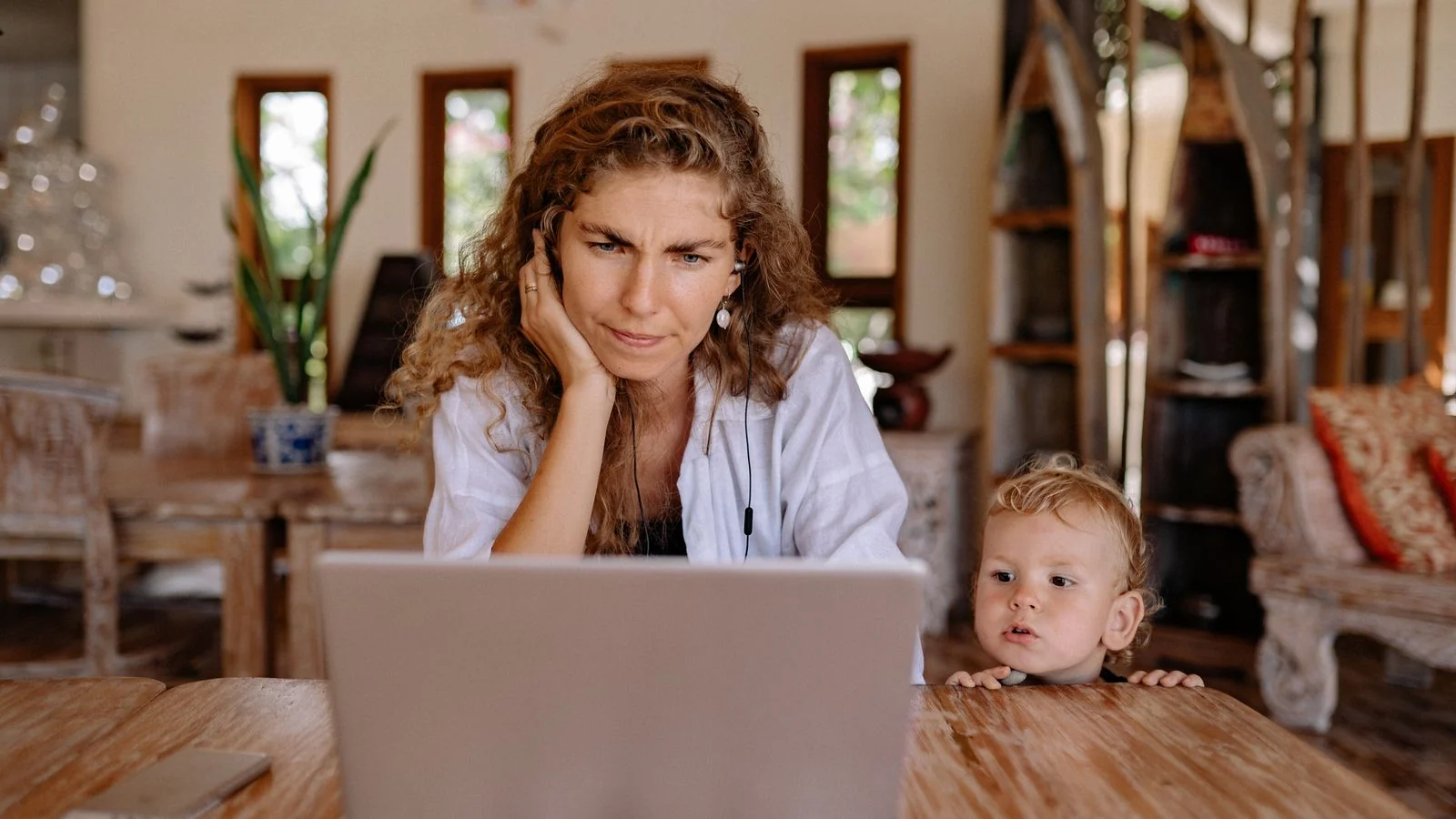 Mother and young son looking at a laptop together at a wooden table, a parenting blog's core reader
