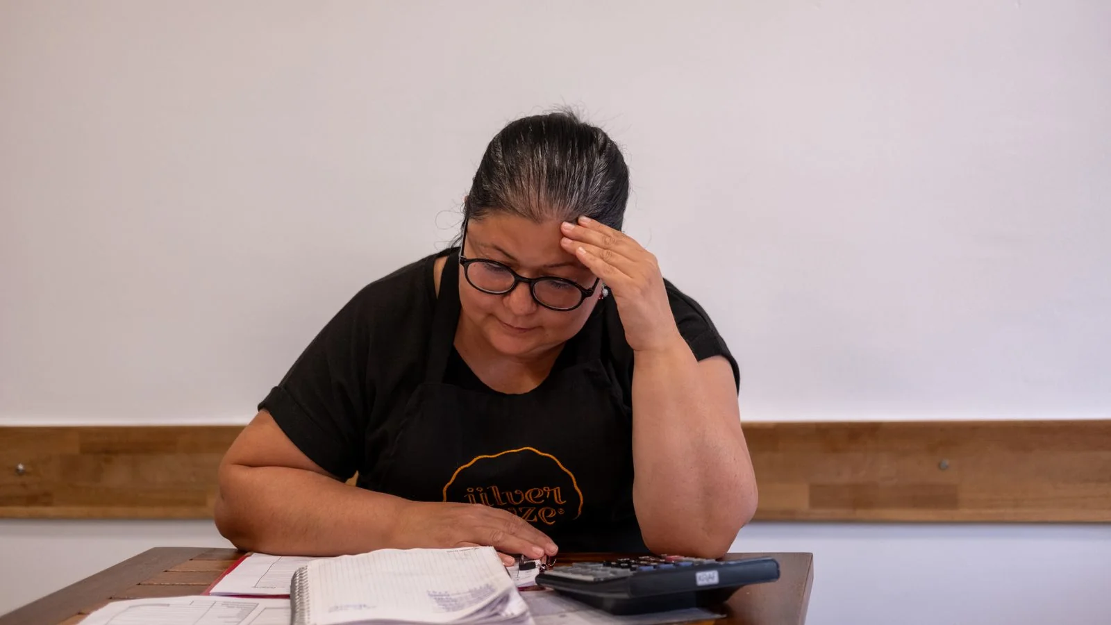 Small business owner reviewing financial figures with a calculator at a desk