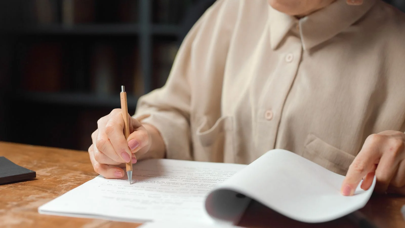 A senior editor reviewing and marking up a manuscript with a green marker