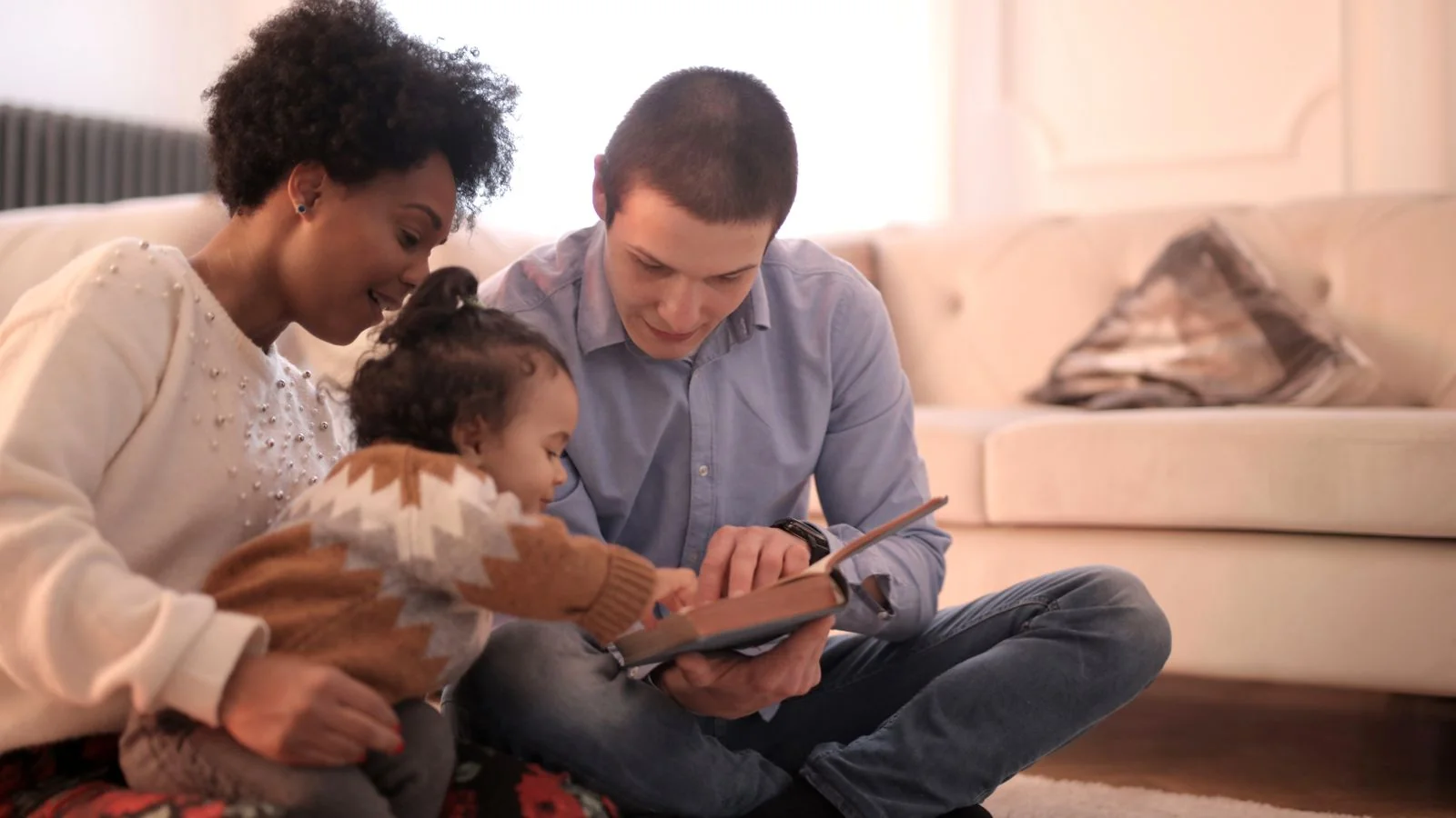 Family reading a book together on a couch, the broad household audience Parade writes for