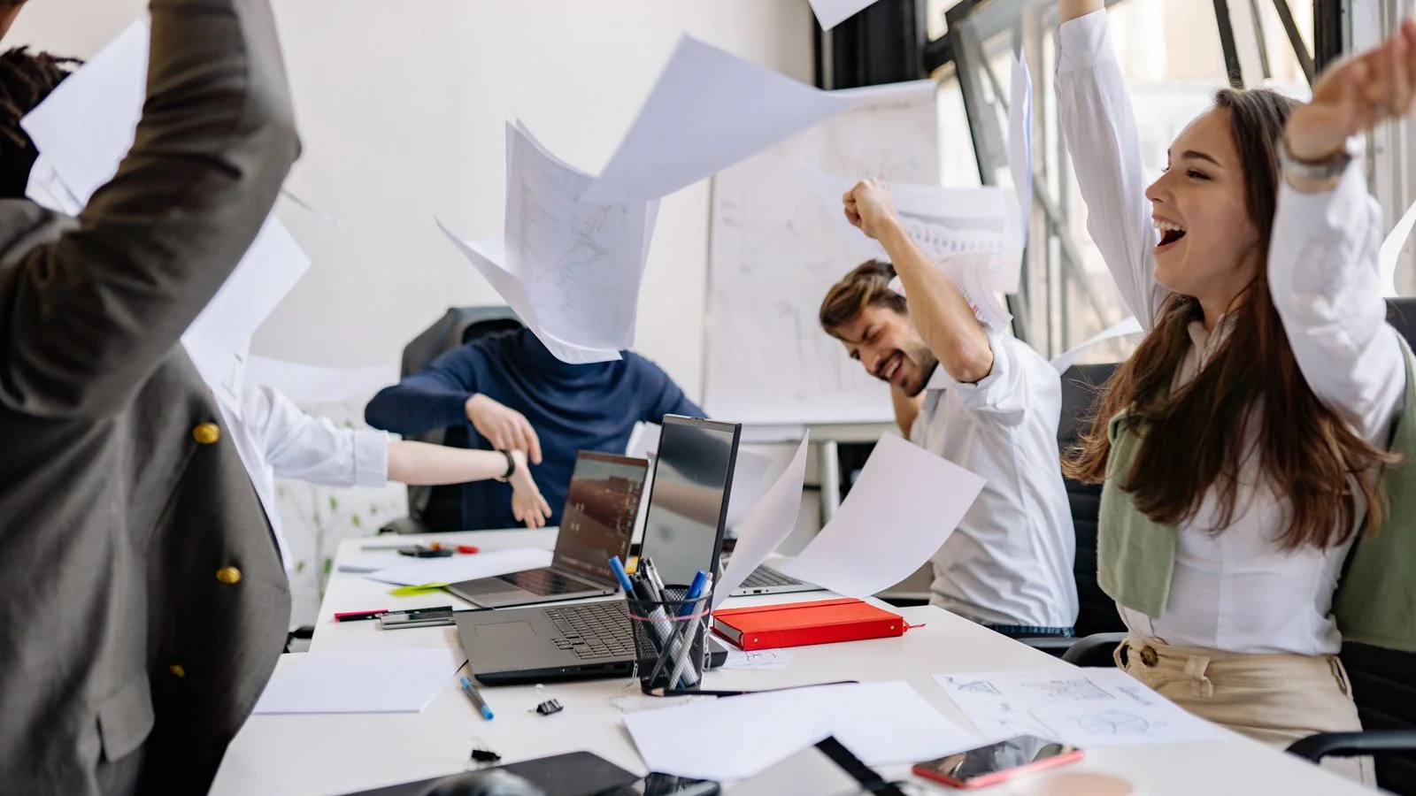 Colleagues celebrating in an office as papers fly, the moment an agency lands a PRWeek award