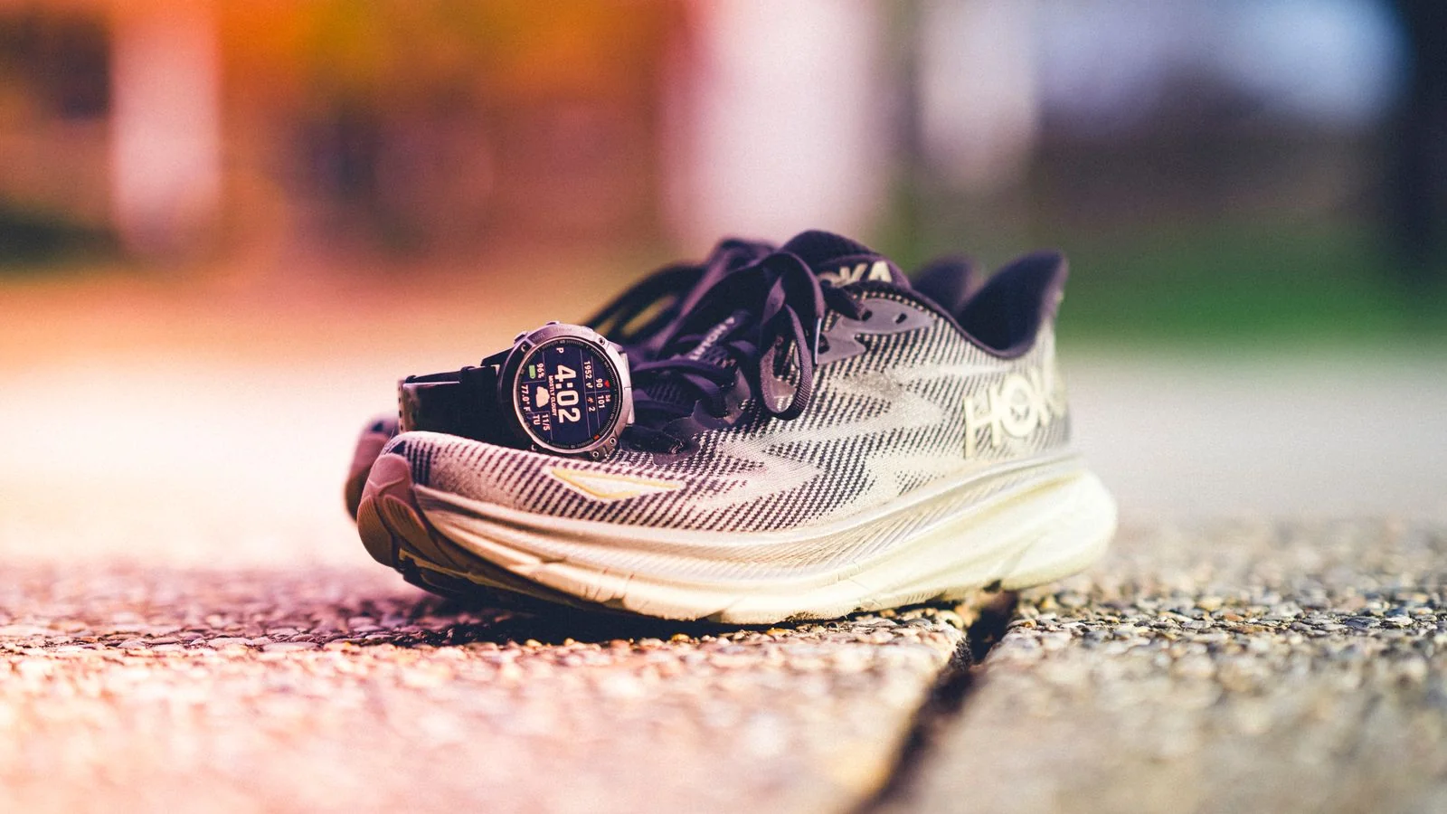 A pair of running shoes beside a GPS watch on a sunny track, the kind of gear Runner's World tests before it recommends