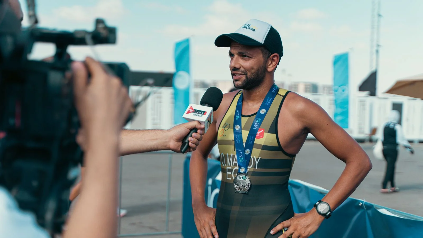 Triathlete wearing a medal being interviewed by a reporter after a race
