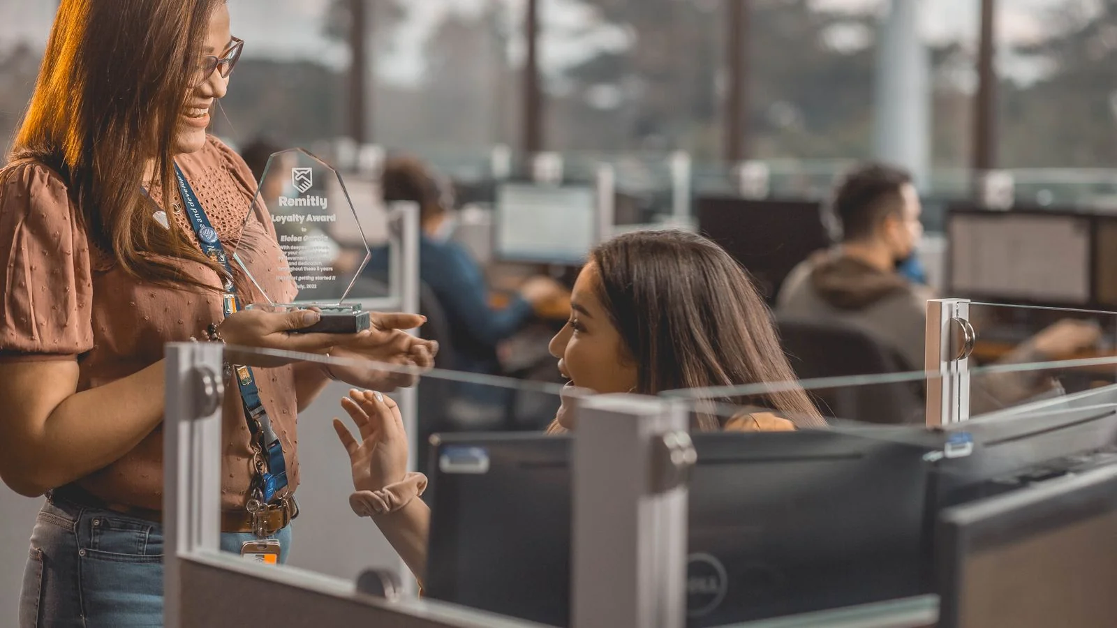 Coworkers sharing an award moment in an office, the community of strivers SUCCESS Magazine writes for
