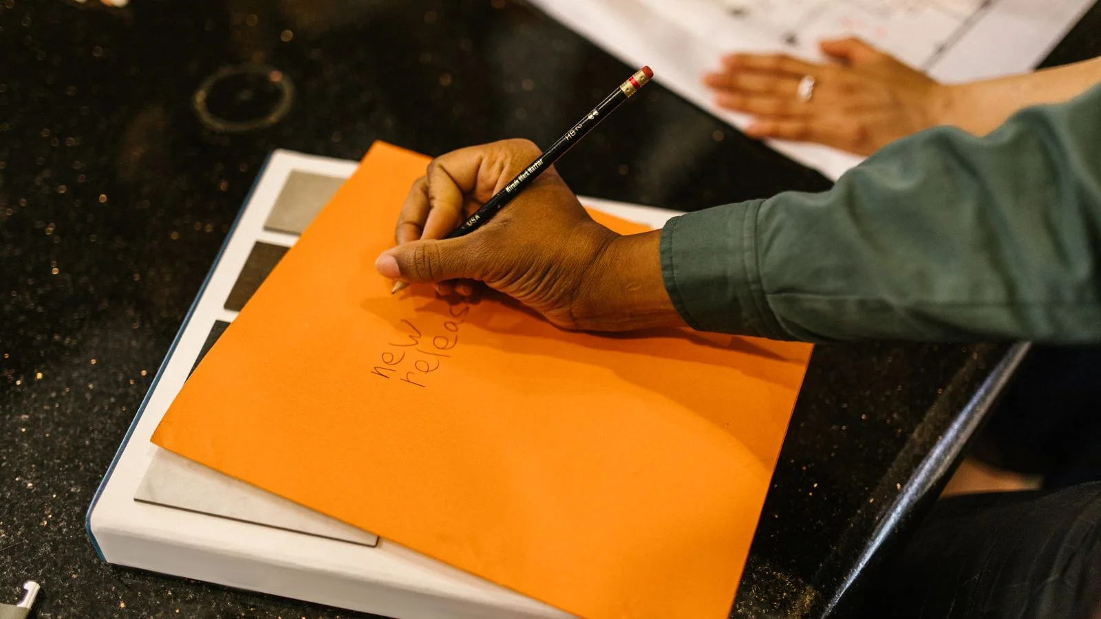 A hand writing a note by pencil on an envelope, the start of a personalized pitch