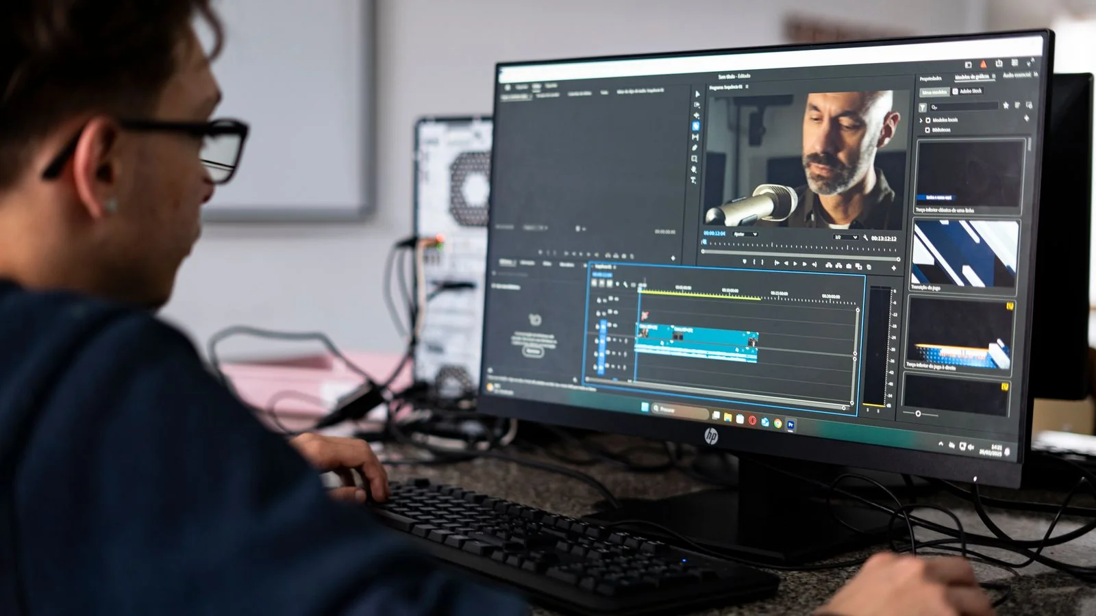 Video editor working at a desktop computer in a modern office, like a busy trade newsroom