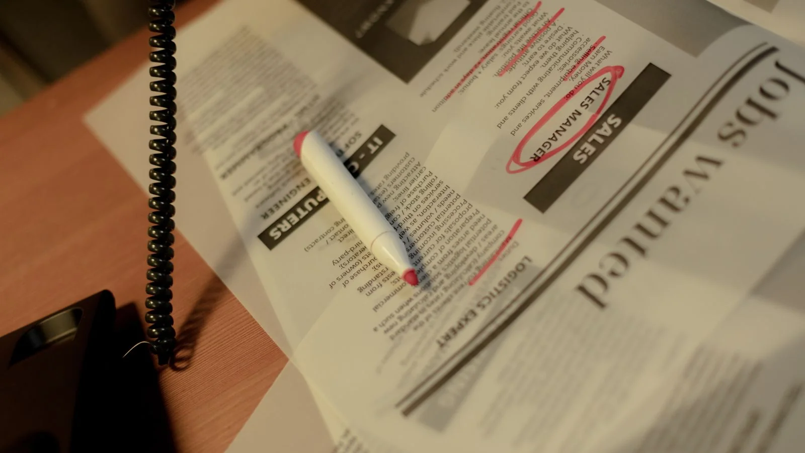 Newspaper classifieds page with a red marker and corded phone, old-school tip hunting