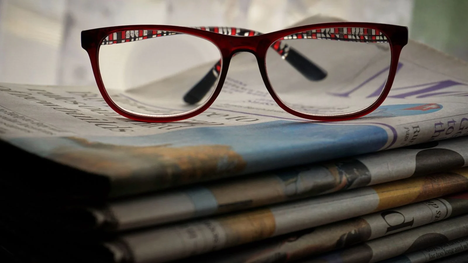 Reading glasses resting on a stack of newspapers, a reminder to study the publication before pitching it