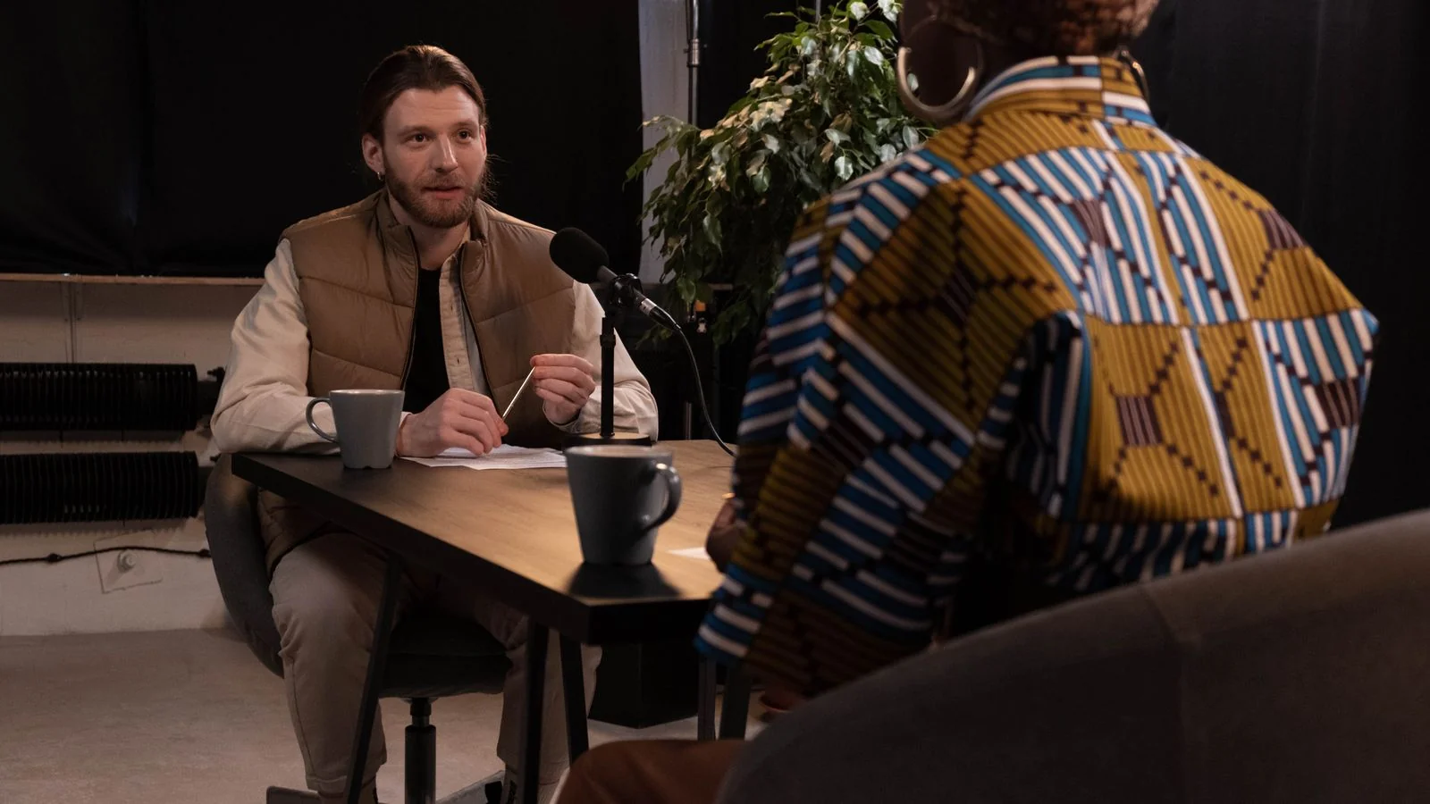Two people in conversation across a table with microphones, the practitioner voice DataDecisionMakers publishes