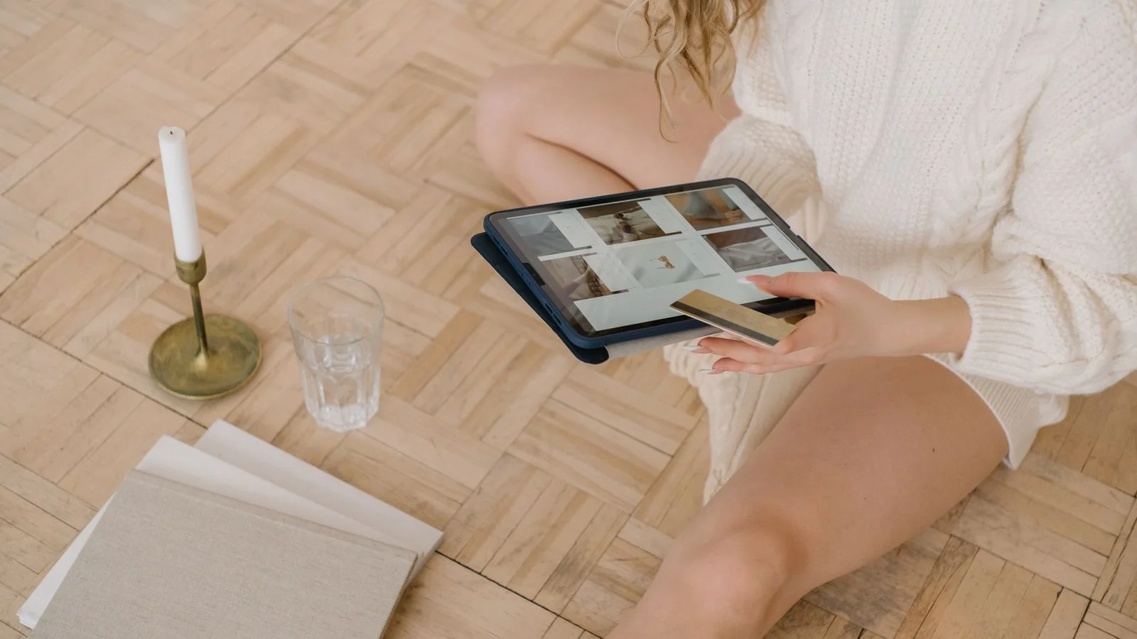 Woman browsing an online clothing store on a tablet with a bank card beside her
