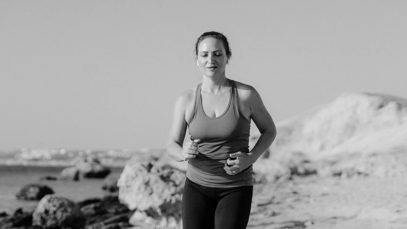 A woman running outdoors at the waterline, the kind of real-world fitness story the publication builds around