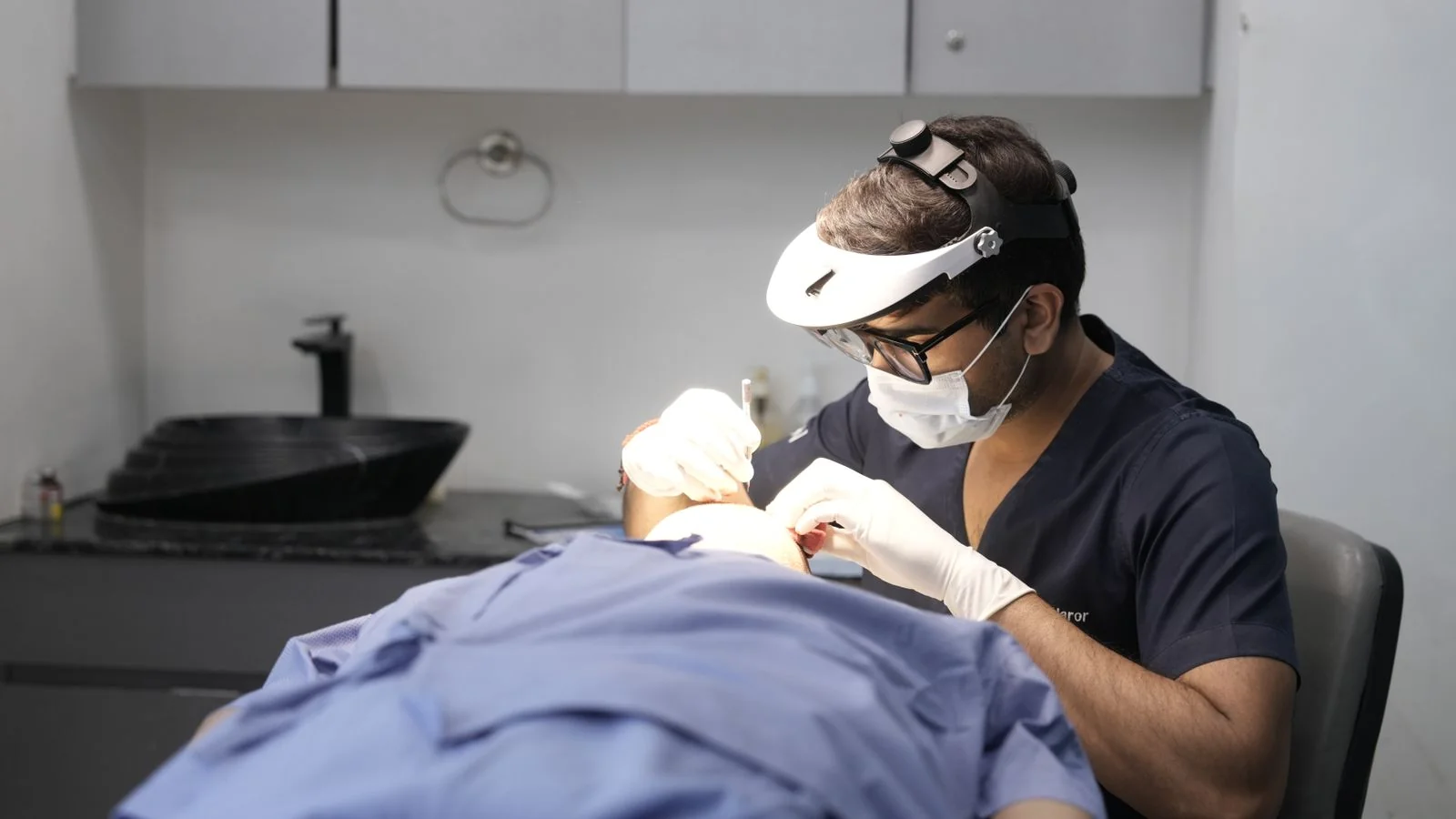 Dermatologist examining a patient in a clinic, the kind of practice a credential line has to point to
