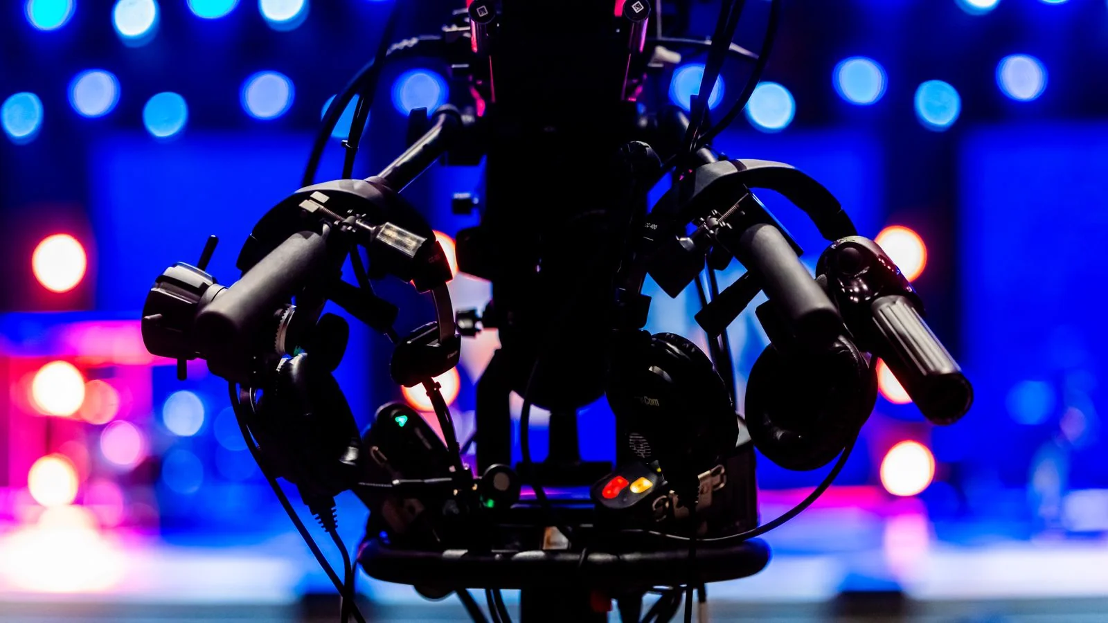 Professional video camera in silhouette against colorful stage lights in a studio