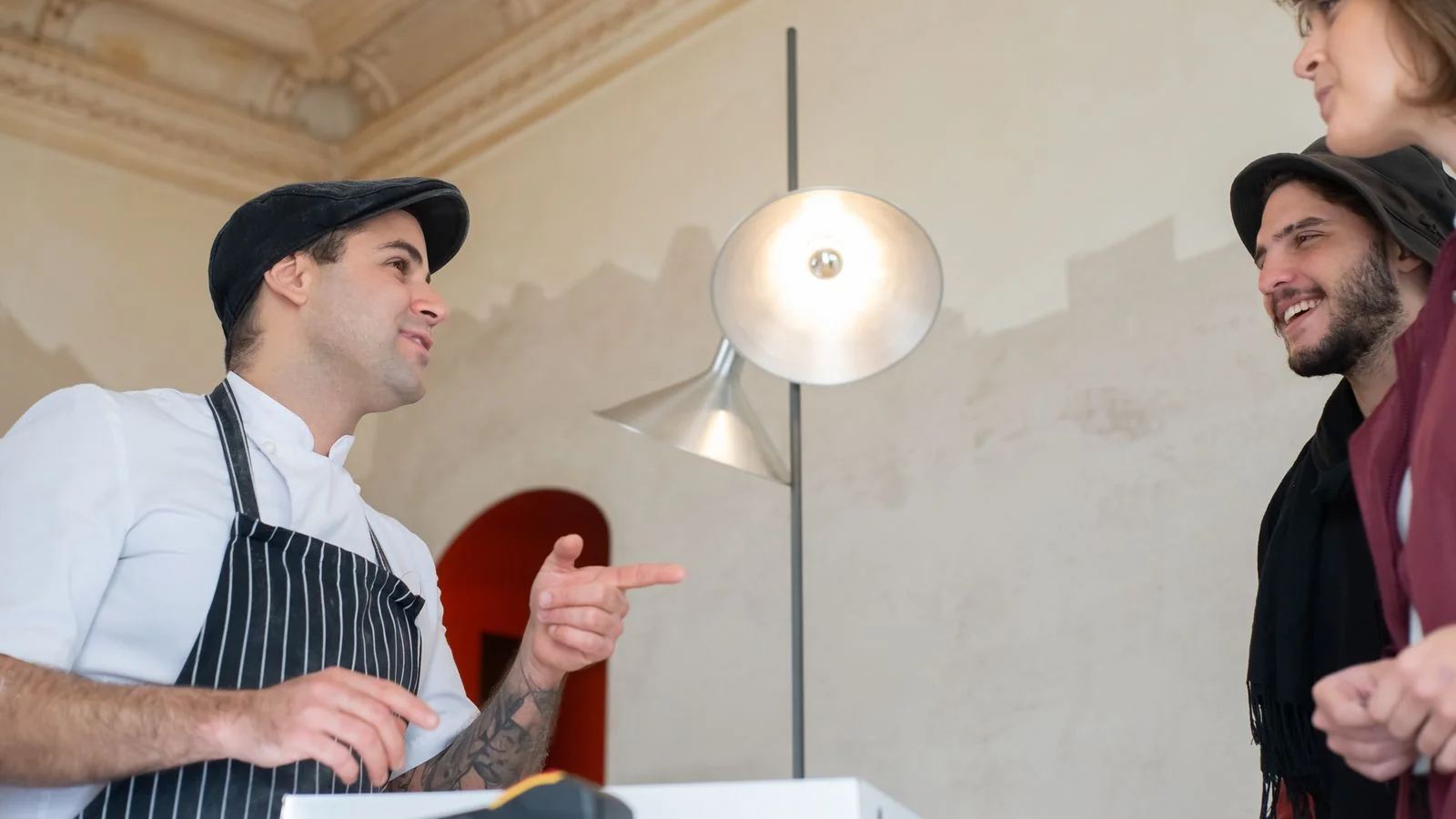 Chef in a white hat chatting with happy customers in a restaurant dining room