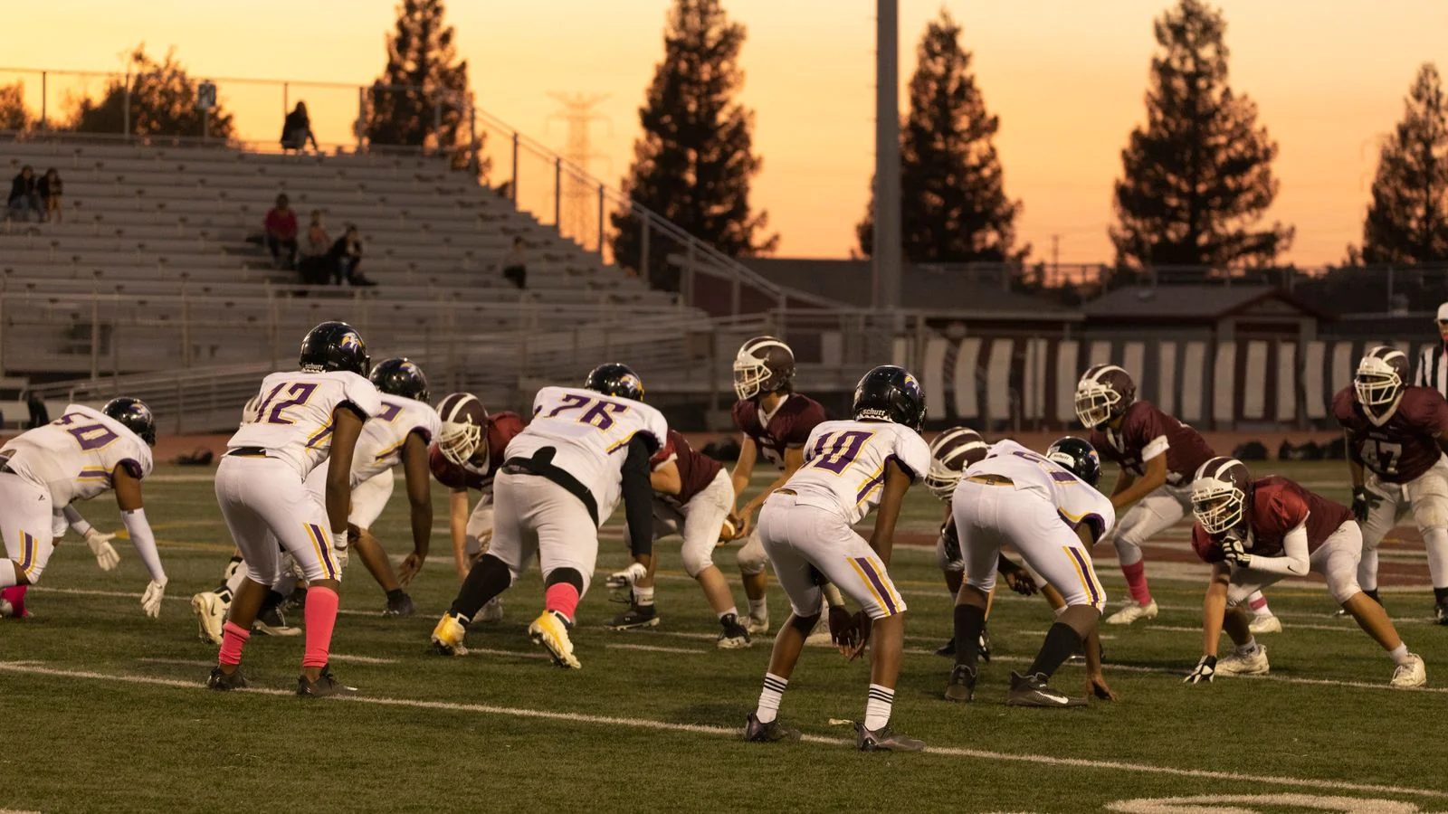 American football game under stadium lights at sunset in a local stadium