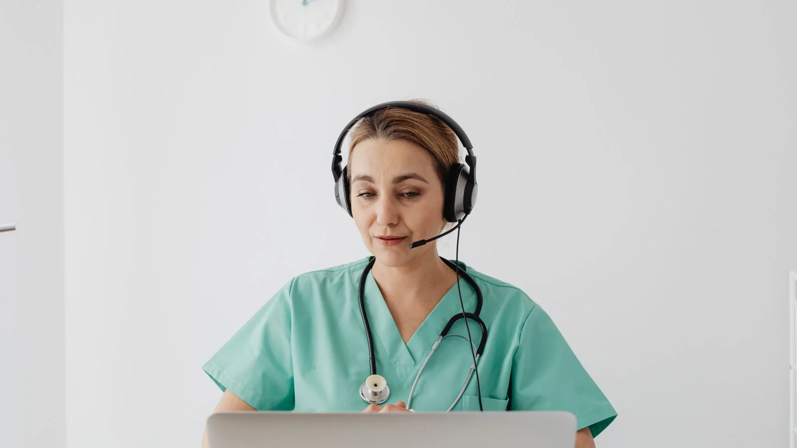 Female doctor in scrubs on a video consultation using her laptop