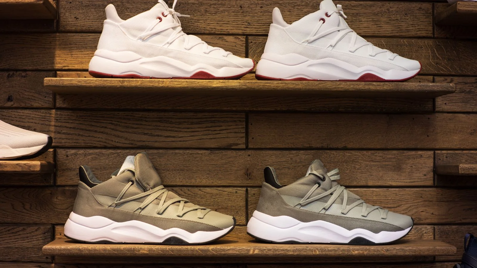 Rows of sneakers lined up on wooden shelves in a footwear store