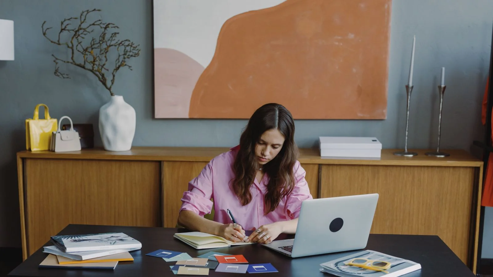 Woman working on a project at a home office desk with a laptop and color swatches